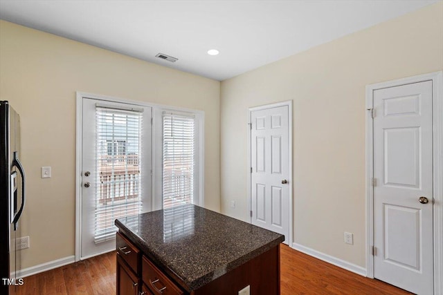 229 Michigan Ave, Cary, NC 27519 - kitchen with refrigerator with ice dispenser, baseboards, dark wood finished floors, a center island, and dark stone countertops