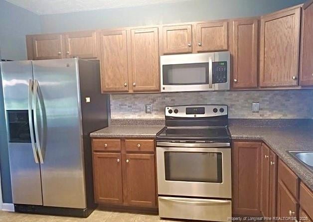 1824 Ponderosa Trl, Cameron, NC 28326 - kitchen with appliances with stainless steel finishes, dark countertops, decorative backsplash, and brown cabinets