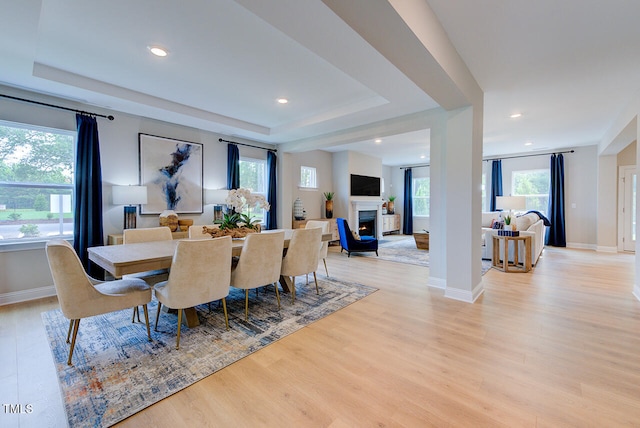 2512 Stonington Dr, Cary, NC 27523 - dining area with plenty of natural light, light wood-style floors, a lit fireplace, a tray ceiling, and recessed lighting