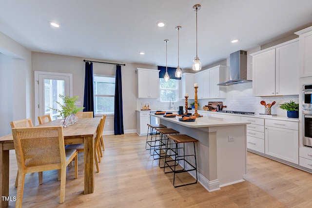 2512 Stonington Dr, Cary, NC 27523 - kitchen with wall chimney range hood, a center island, backsplash, gas cooktop, and light wood finished floors
