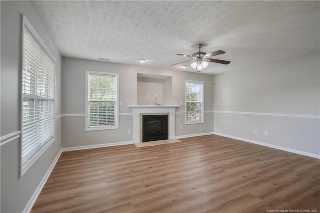 153 Abbey Ln, Raeford, NC 28376 - unfurnished living room with a textured ceiling, wood finished floors, a ceiling fan, baseboards, and a fireplace with flush hearth
