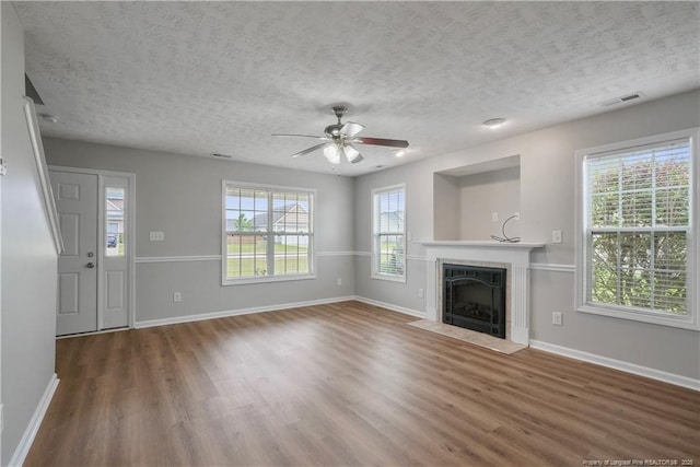 153 Abbey Ln, Raeford, NC 28376 - unfurnished living room with wood finished floors, a ceiling fan, a textured ceiling, baseboards, and a high end fireplace