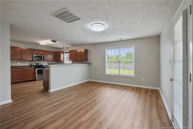 153 Abbey Ln, Raeford, NC 28376 - kitchen with appliances with stainless steel finishes, plenty of natural light, wood finished floors, baseboards, and a textured ceiling