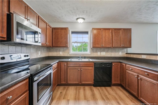 153 Abbey Ln, Raeford, NC 28376 - kitchen with stainless steel appliances, a sink, light wood-type flooring, dark countertops, and a textured ceiling