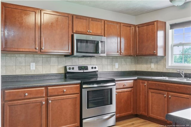 153 Abbey Ln, Raeford, NC 28376 - kitchen with appliances with stainless steel finishes, a sink, dark countertops, and brown cabinets