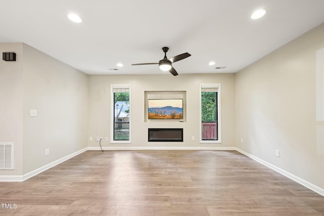 124 Twin Oaks Pl, Cary, NC 27511 - unfurnished living room featuring plenty of natural light, light wood-type flooring, a ceiling fan, recessed lighting, and a glass covered fireplace