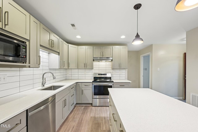 124 Twin Oaks Pl, Cary, NC 27511 - kitchen featuring appliances with stainless steel finishes, a sink, light wood-style flooring, under cabinet range hood, and light countertops