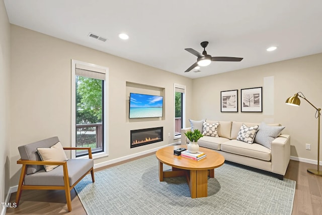 124 Twin Oaks Pl, Cary, NC 27511 - living room featuring healthy amount of natural light, wood finished floors, a glass covered fireplace, baseboards, and recessed lighting