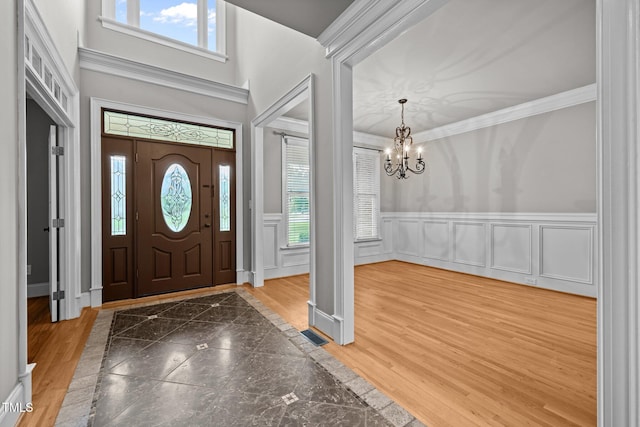 1124 Kalworth Rd, Wake Forest, NC 27587 - entrance foyer featuring inlaid floor details, a chandelier, a wainscoted wall, a decorative wall, and crown molding