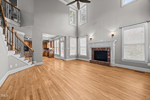 1124 Kalworth Rd, Wake Forest, NC 27587 - unfurnished living room with ceiling fan, light wood-style floors, a brick fireplace, stairway, and a towering ceiling