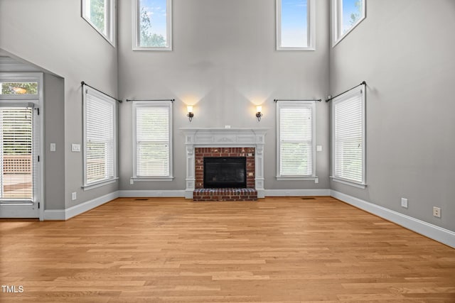 1124 Kalworth Rd, Wake Forest, NC 27587 - unfurnished living room featuring a towering ceiling, plenty of natural light, a fireplace, and light wood-type flooring
