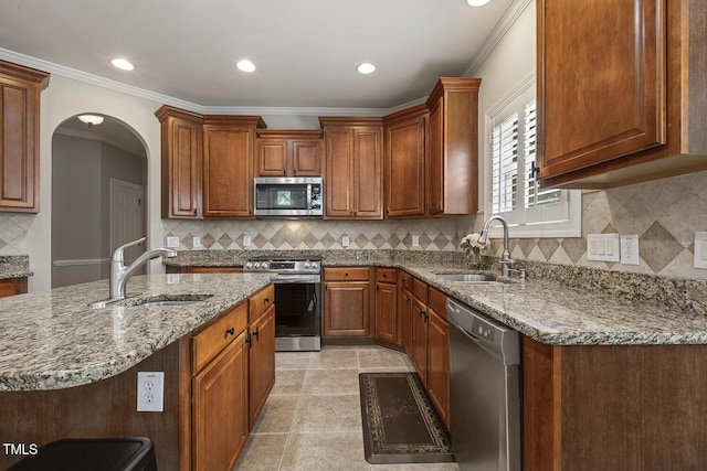 5516 Colonial Oaks Dr, Apex, NC 27539 - kitchen featuring stainless steel appliances, a sink, stone counters, arched walkways, and crown molding