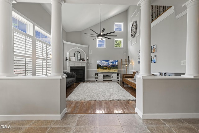 5516 Colonial Oaks Dr, Apex, NC 27539 - living room featuring decorative columns, a ceiling fan, high vaulted ceiling, a glass covered fireplace, and baseboards