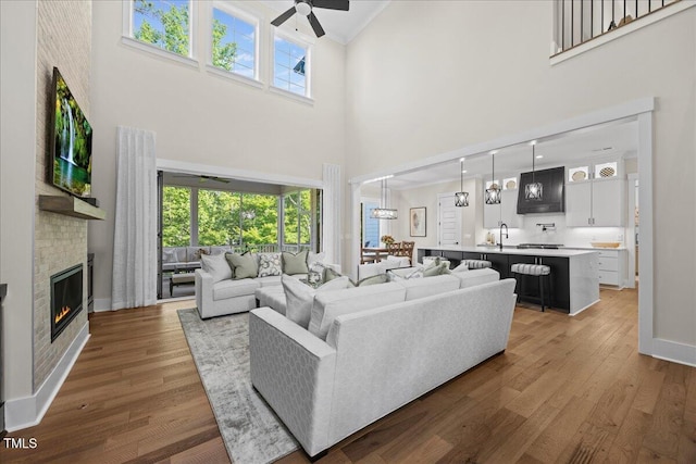 111 Stone Park Dr, Wake Forest, NC 27587 - living area with a towering ceiling, a ceiling fan, wood finished floors, a glass covered fireplace, and baseboards