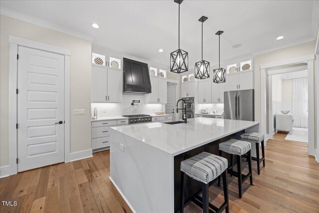 111 Stone Park Dr, Wake Forest, NC 27587 - kitchen with freestanding refrigerator, premium range hood, light wood-style flooring, a large island, and glass insert cabinets
