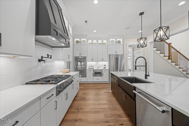 111 Stone Park Dr, Wake Forest, NC 27587 - kitchen featuring stainless steel appliances, wall chimney range hood, a sink, glass insert cabinets, and tasteful backsplash