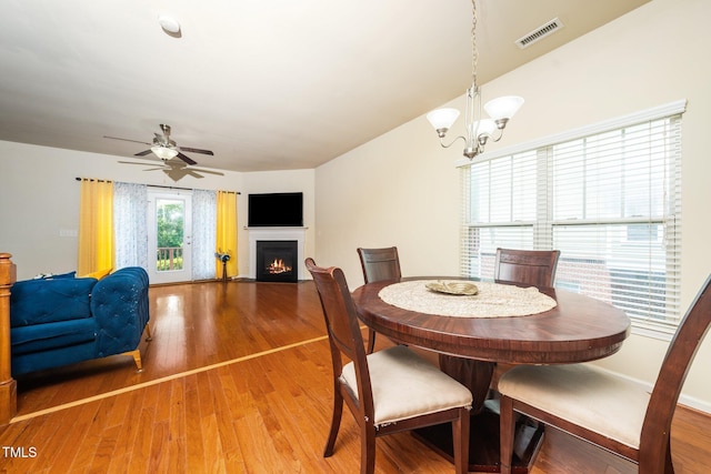 1017 Frank Page Dr, Cary, NC 27511 - dining room featuring a warm lit fireplace, a chandelier, light wood-type flooring, and ceiling fan