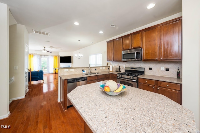 1017 Frank Page Dr, Cary, NC 27511 - kitchen with appliances with stainless steel finishes, a sink, a peninsula, open floor plan, and backsplash