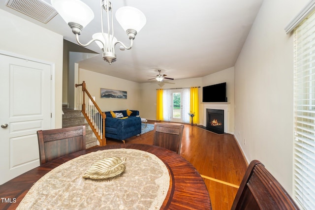 1017 Frank Page Dr, Cary, NC 27511 - dining room with wood finished floors, a fireplace with flush hearth, a chandelier, and a ceiling fan