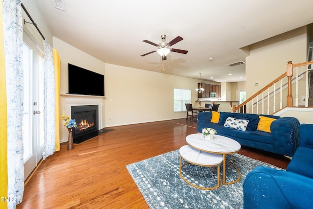 1017 Frank Page Dr, Cary, NC 27511 - living room featuring ceiling fan, a fireplace with flush hearth, wood finished floors, stairs, and baseboards