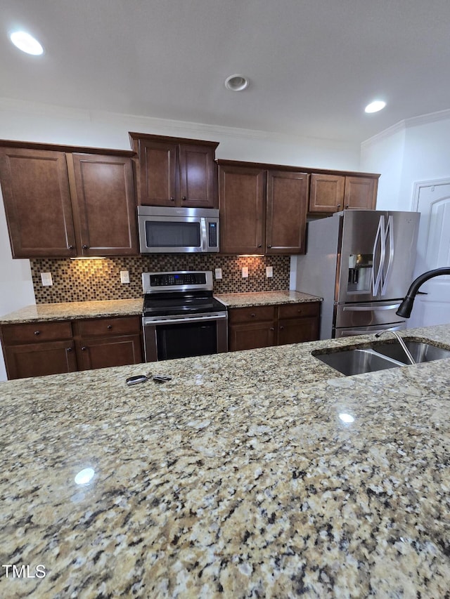 2511 Dalmahoy Ln, Fuquay Varina, NC 27526 - kitchen with appliances with stainless steel finishes, a sink, light stone counters, backsplash, and crown molding