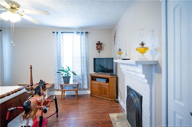 208 W Thompson St E, Fairmont, NC 28340 - living room featuring a ceiling fan, dark wood-style flooring, a textured ceiling, a fireplace, and baseboards
