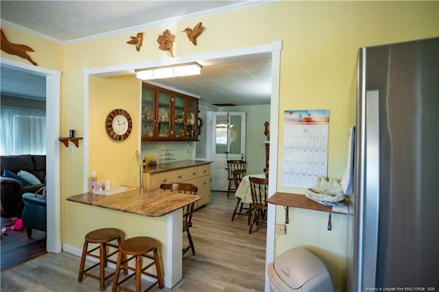 208 W Thompson St E, Fairmont, NC 28340 - kitchen with freestanding refrigerator, light wood-type flooring, ornamental molding, a breakfast bar, and glass insert cabinets