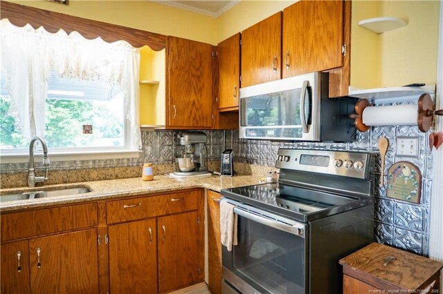 208 W Thompson St E, Fairmont, NC 28340 - kitchen with stainless steel appliances, a sink, tasteful backsplash, brown cabinets, and light stone countertops