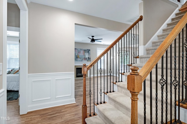 112 Briarfield Dr, Apex, NC 27502 - stairway featuring a ceiling fan, wood finished floors, wainscoting, and a glass covered fireplace