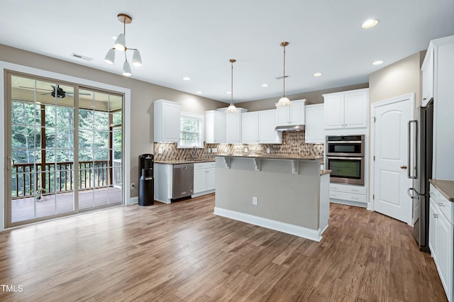 112 Briarfield Dr, Apex, NC 27502 - kitchen with appliances with stainless steel finishes, a kitchen breakfast bar, decorative backsplash, white cabinetry, and light wood-style floors