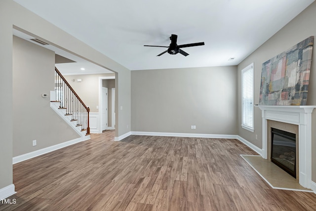 112 Briarfield Dr, Apex, NC 27502 - unfurnished living room with a ceiling fan, wood finished floors, stairway, and a glass covered fireplace