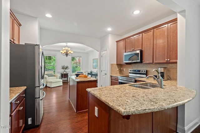 1612 Old Bramble Ln, Fuquay Varina, NC 27526 - kitchen featuring stainless steel appliances, arched walkways, dark wood-style flooring, a sink, and a peninsula