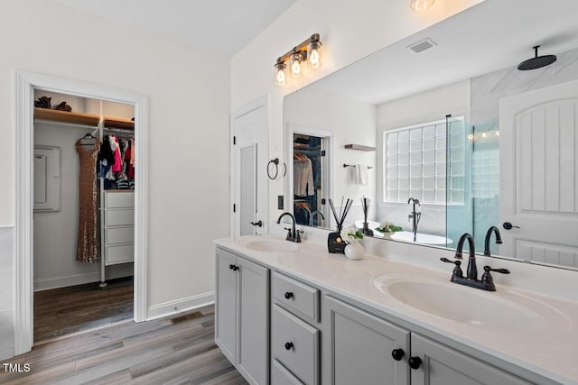 1612 Old Bramble Ln, Fuquay Varina, NC 27526 - bathroom featuring double vanity, a walk in closet, wood finished floors, a shower with shower door, and baseboards