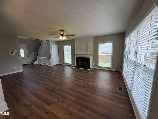 4903 Bridgewood Dr, Durham, NC 27713 - unfurnished living room featuring a textured ceiling, dark wood-type flooring, a ceiling fan, a large fireplace, and stairs