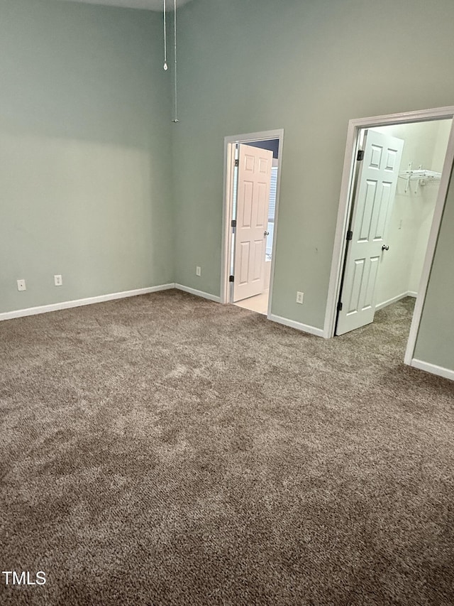 1017 Red Hat Ln, Durham, NC 27713 - unfurnished bedroom with carpet, a towering ceiling, a walk in closet, and baseboards
