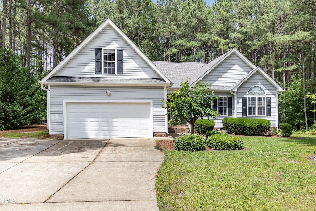 25 Spicetree Ct, Youngsville, NC 27596 - view of front facade with a garage, driveway, a front lawn, view of wooded area, and a shingled roof