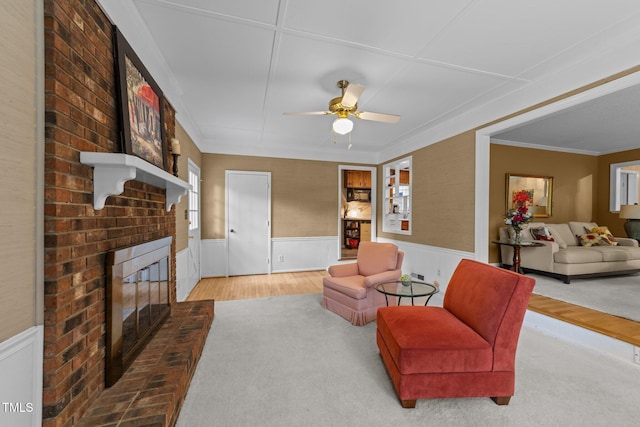 1040 Ivy Ln, Cary, NC 27511 - living area with a wainscoted wall, a brick fireplace, a ceiling fan, and crown molding