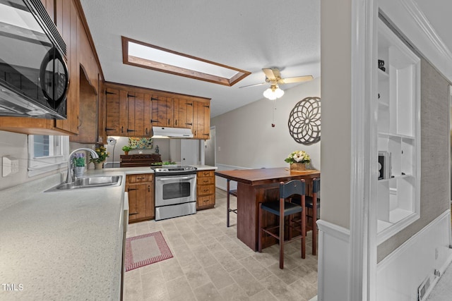 1040 Ivy Ln, Cary, NC 27511 - kitchen featuring stainless steel range with electric stovetop, black microwave, a ceiling fan, light countertops, and brown cabinets