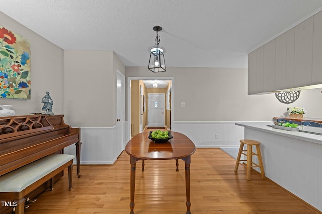 1040 Ivy Ln, Cary, NC 27511 - dining room with light wood-style floors, wainscoting, and a textured ceiling