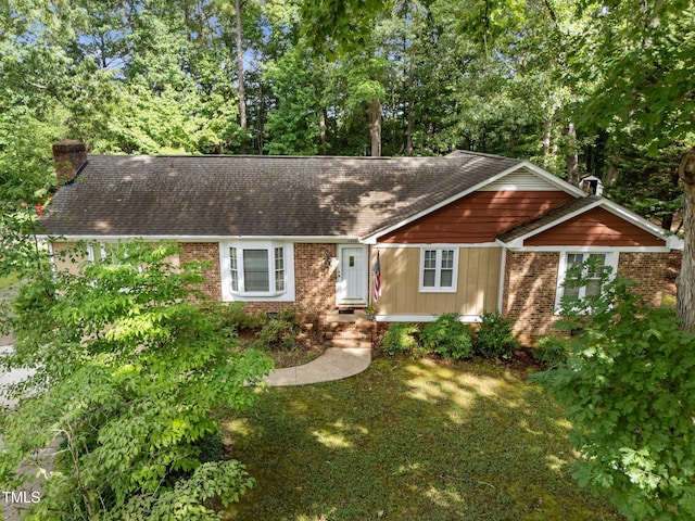 1040 Ivy Ln, Cary, NC 27511 - view of front of home featuring a chimney, brick siding, a shingled roof, and view of wooded area
