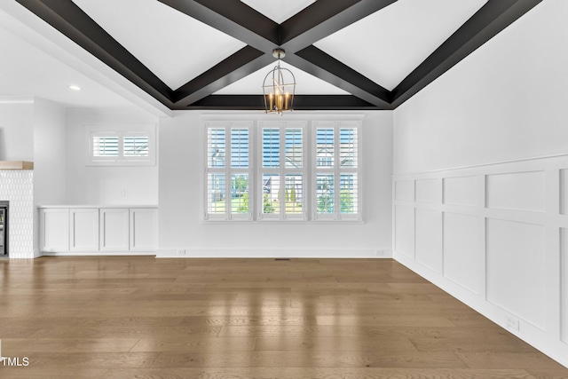121 Nate Ct, Wake Forest, NC 27587 - unfurnished living room featuring a chandelier, beamed ceiling, a decorative wall, healthy amount of natural light, and wood finished floors