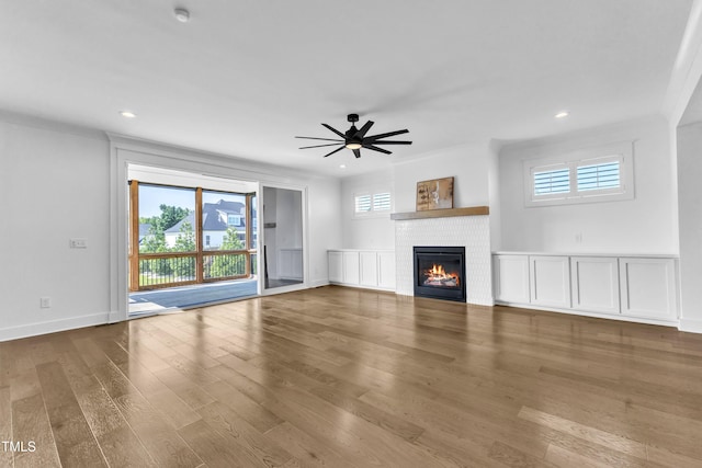 121 Nate Ct, Wake Forest, NC 27587 - unfurnished living room with a brick fireplace, wood finished floors, a ceiling fan, recessed lighting, and crown molding