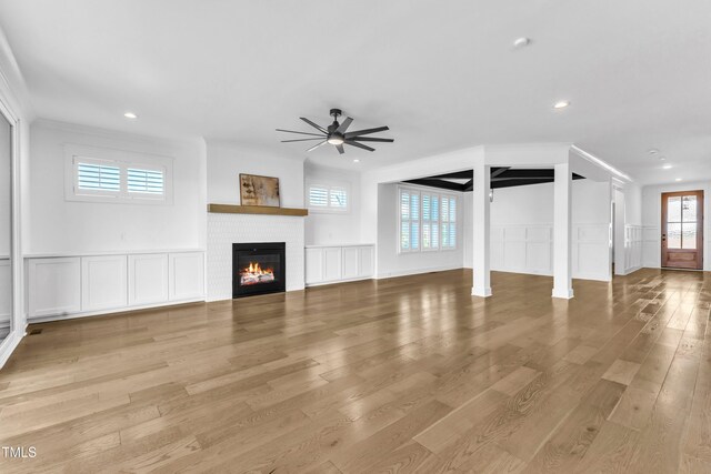 121 Nate Ct, Wake Forest, NC 27587 - unfurnished living room featuring ceiling fan, a decorative wall, light wood-type flooring, a glass covered fireplace, and recessed lighting
