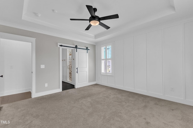 121 Nate Ct, Wake Forest, NC 27587 - unfurnished bedroom featuring a tray ceiling, a barn door, carpet, ornamental molding, and a ceiling fan
