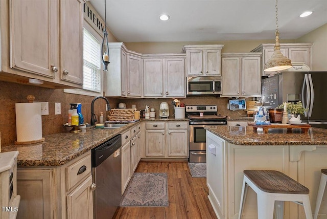 15 Scuppernong Ln, Lillington, NC 27546 - kitchen with stainless steel appliances, a sink, light wood finished floors, a kitchen bar, and dark stone counters