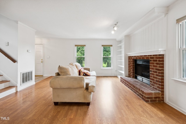 3405 E Jameson Rd, Raleigh, NC 27604 - living room with built in features, wood finished floors, stairway, a brick fireplace, and crown molding