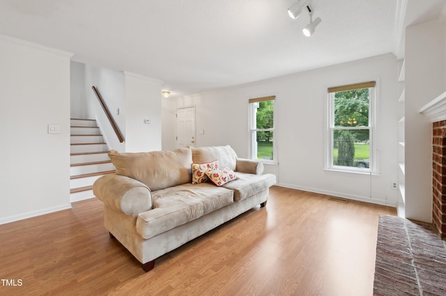3405 E Jameson Rd, Raleigh, NC 27604 - living area with light wood-style flooring, stairs, baseboards, a brick fireplace, and crown molding