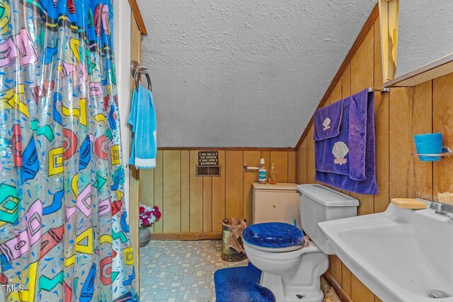 517 E 14th St, Lumberton, NC 28358 - full bath featuring a sink, a textured ceiling, toilet, wooden walls, and a shower with curtain