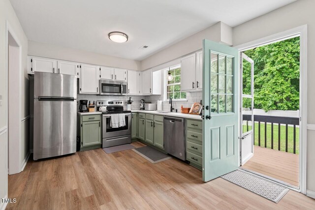 411 Buxton St, Durham, NC 27713 - kitchen featuring appliances with stainless steel finishes, light wood-style flooring, decorative backsplash, light countertops, and white cabinetry