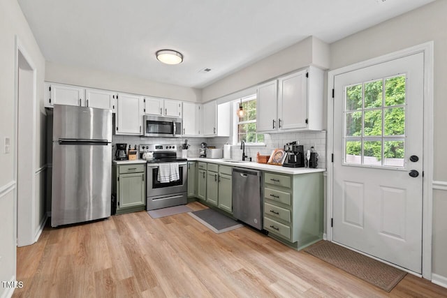 411 Buxton St, Durham, NC 27713 - kitchen with appliances with stainless steel finishes, green cabinets, decorative backsplash, and light wood-style floors